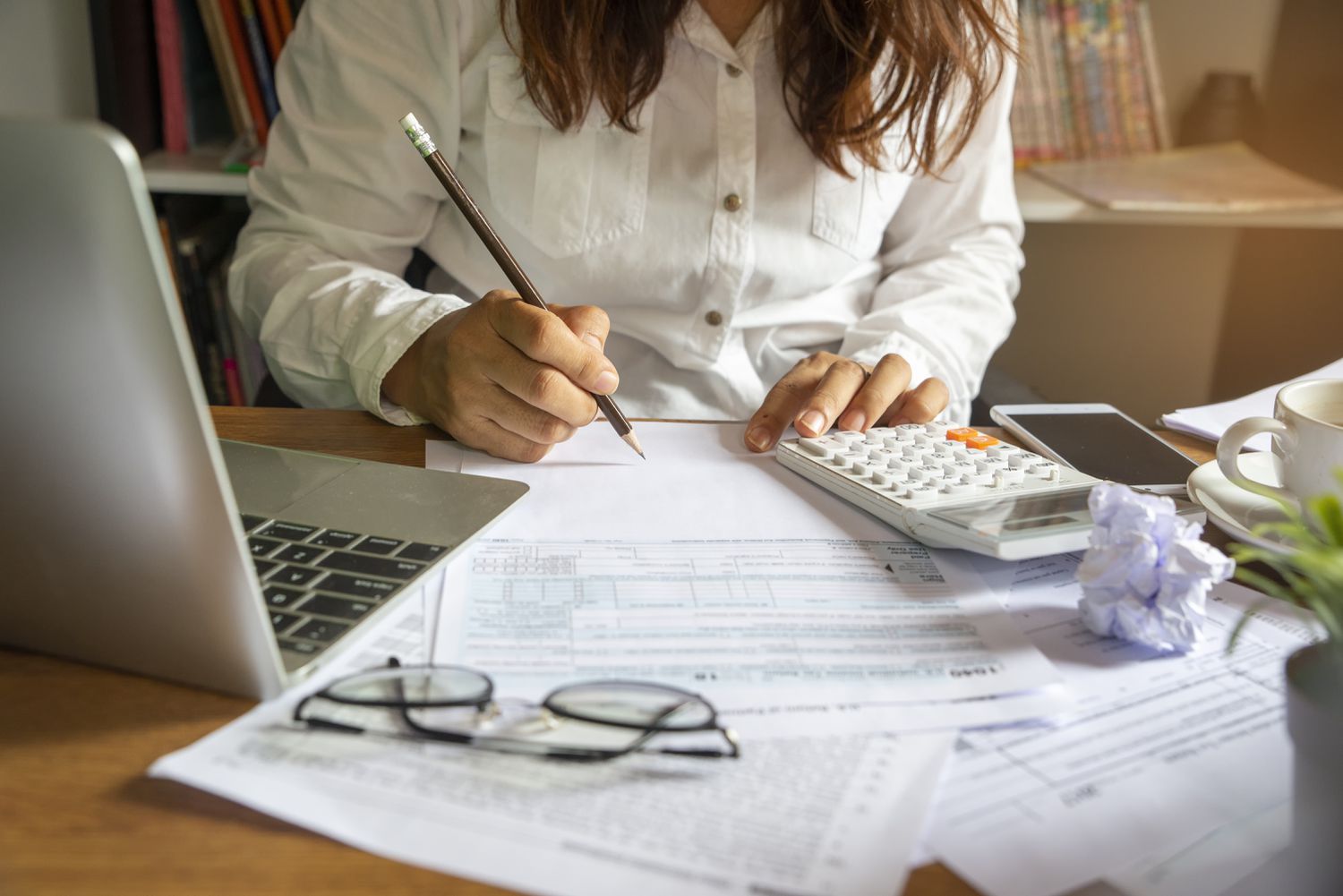 Tax professional reviewing documents at desk with laptop and calculator for tax preparation services